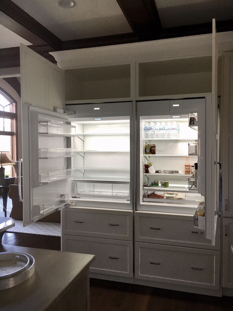 Inspiration for a large transitional l-shaped dark wood floor and brown floor eat-in kitchen remodel with a farmhouse sink, recessed-panel cabinets, white cabinets, granite countertops, white backsplash, ceramic backsplash, stainless steel appliances and an island
