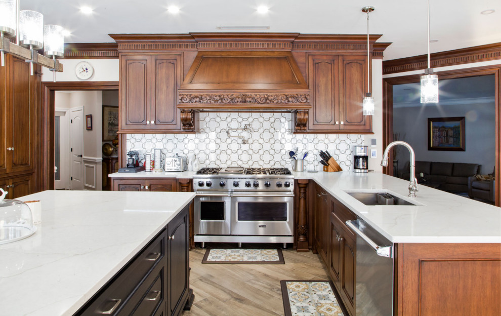 Inspiration for a large traditional u-shaped eat-in kitchen in New York with a drop-in sink, shaker cabinets, medium wood cabinets, quartz benchtops, white splashback, engineered quartz splashback, stainless steel appliances, light hardwood floors, with island, brown floor, white benchtop and wallpaper.