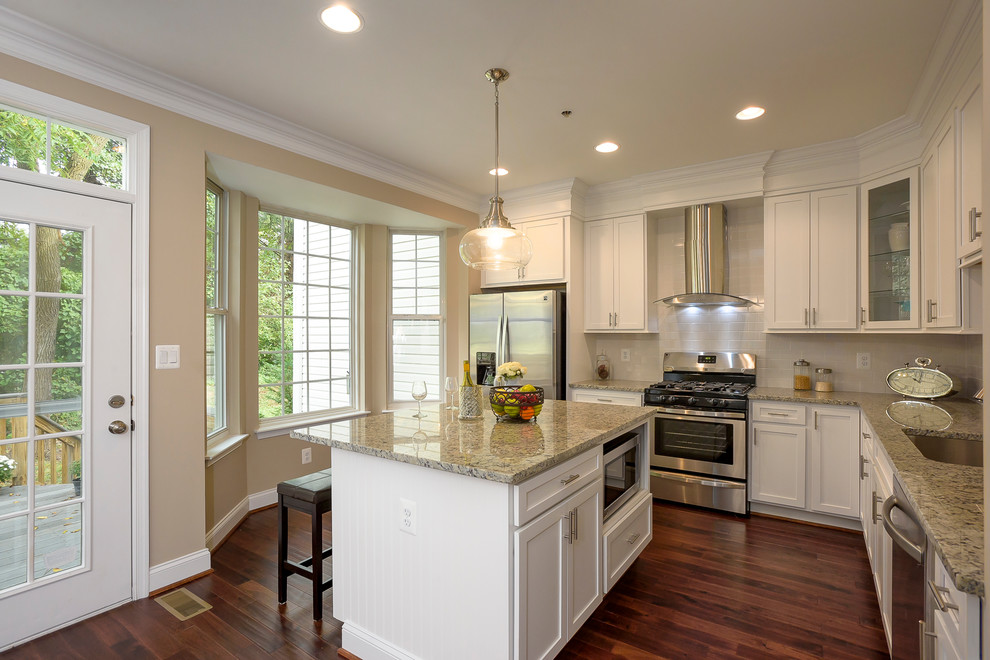 Example of a mid-sized transitional l-shaped dark wood floor and red floor eat-in kitchen design in Baltimore with an undermount sink, shaker cabinets, white cabinets, granite countertops, beige backsplash, ceramic backsplash, stainless steel appliances and an island