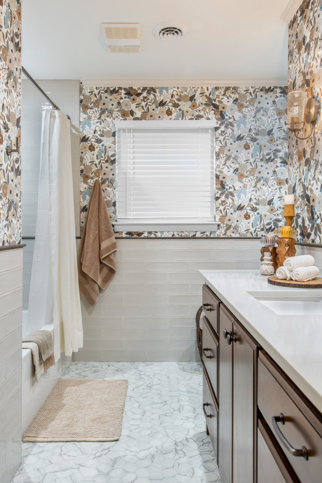 This is an example of a mid-sized transitional 3/4 bathroom in Other with raised-panel cabinets, brown cabinets, an alcove tub, an alcove shower, a two-piece toilet, white tile, glass tile, multi-coloured walls, mosaic tile floors, an undermount sink, quartzite benchtops, grey floor, a shower curtain, white benchtops, a single vanity, a built-in vanity and wallpaper.