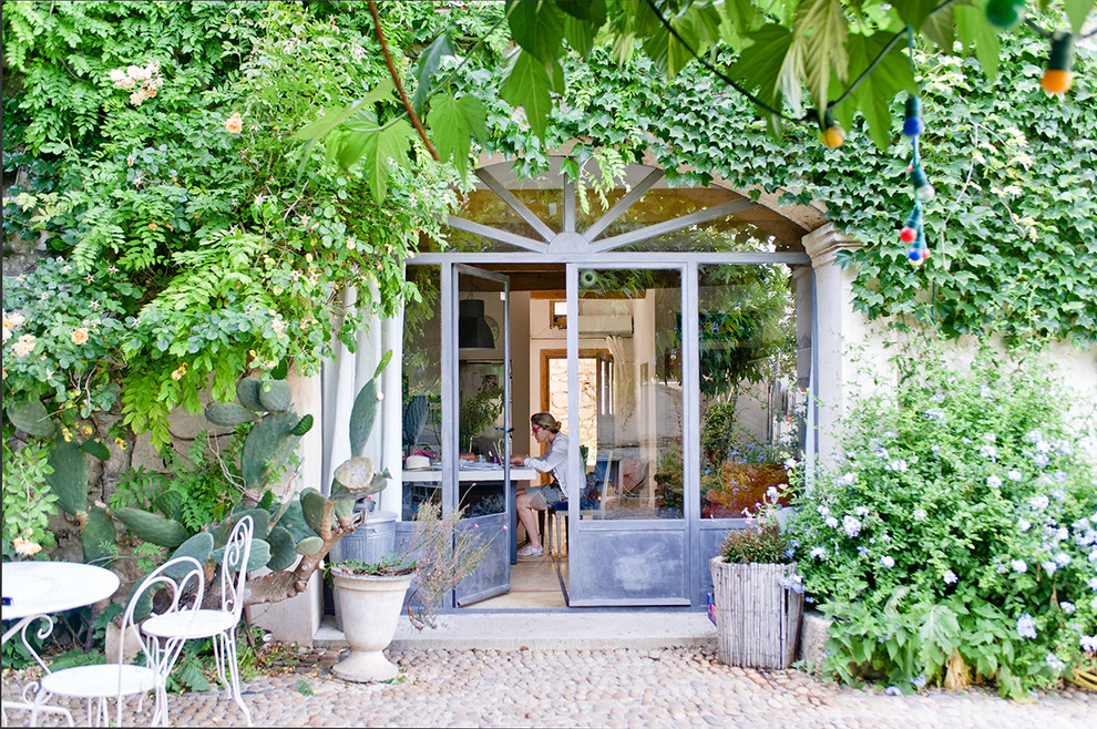 Mid-sized mediterranean backyard shaded garden in Montpellier with natural stone pavers and a container garden for summer.