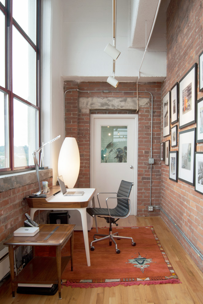 This is an example of an industrial home office in Other with a freestanding desk and light hardwood floors.