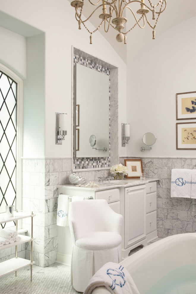 Photo of a traditional bathroom in Other with an undermount sink, raised-panel cabinets, white cabinets, a freestanding tub, white tile, white walls and mosaic tile floors.