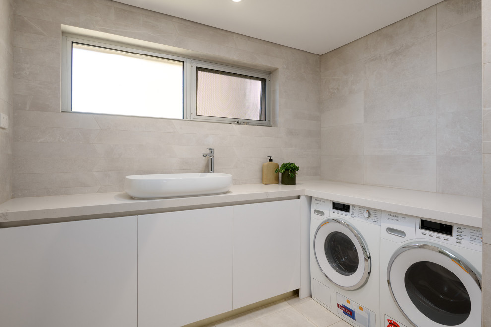 Design ideas for a mid-sized modern l-shaped utility room in Perth with an undermount sink, flat-panel cabinets, white cabinets, quartz benchtops, white benchtop, beige splashback, porcelain splashback, beige walls, porcelain floors, a side-by-side washer and dryer and beige floor.