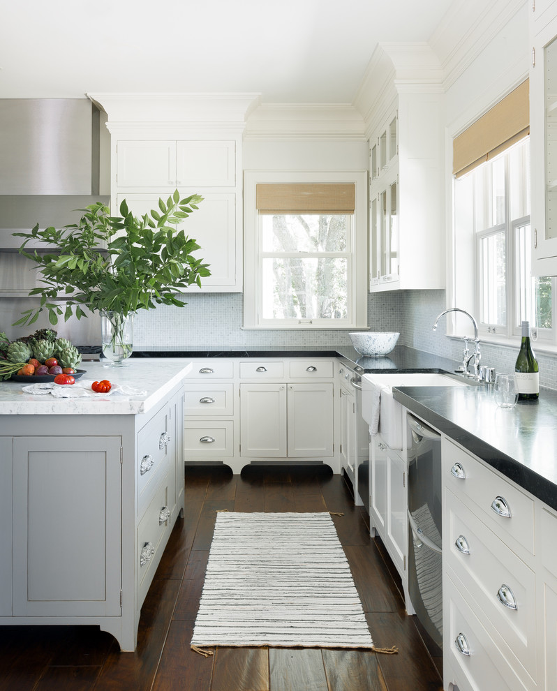 This is an example of a country l-shaped kitchen in San Francisco with with island, a farmhouse sink, shaker cabinets, white cabinets, grey splashback, stainless steel appliances and dark hardwood floors.