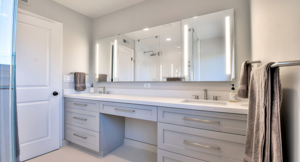 Inspiration for a mid-sized contemporary master bathroom in San Francisco with shaker cabinets, grey cabinets, a corner shower, a two-piece toilet, white tile, porcelain tile, grey walls, porcelain floors, an undermount sink, engineered quartz benchtops, white floor, a hinged shower door and white benchtops.