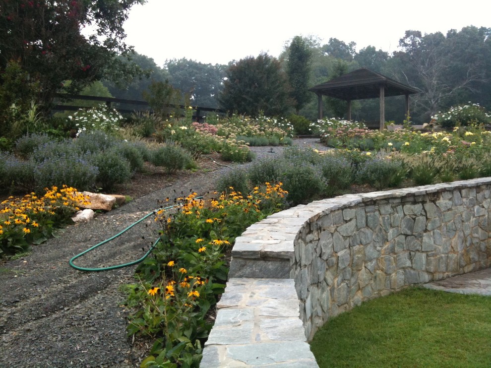 Photo of a large rustic partial sun backyard stone formal garden for summer.