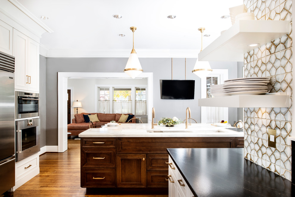 Large transitional u-shaped eat-in kitchen in Other with white splashback, glass tile splashback, stainless steel appliances, medium hardwood floors, with island, brown floor, a farmhouse sink, recessed-panel cabinets, white cabinets and marble benchtops.