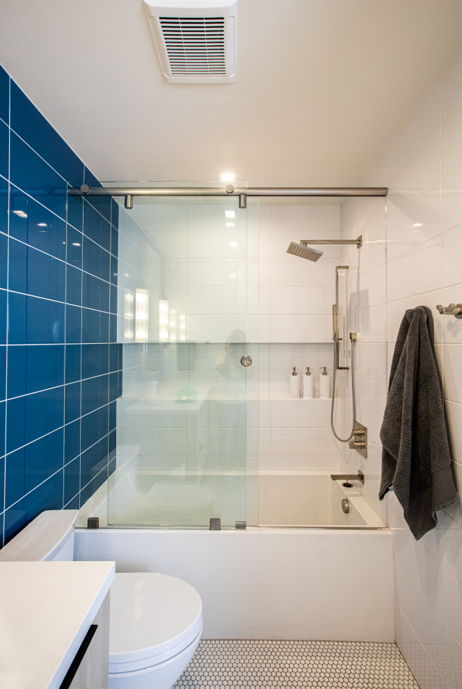 This is an example of a large midcentury family bathroom in Salt Lake City with flat-panel cabinets, light wood cabinets, a shower/bath combination, blue tiles, white walls, mosaic tile flooring, quartz worktops, orange floors, a sliding door, white worktops, a single sink and a floating vanity unit.