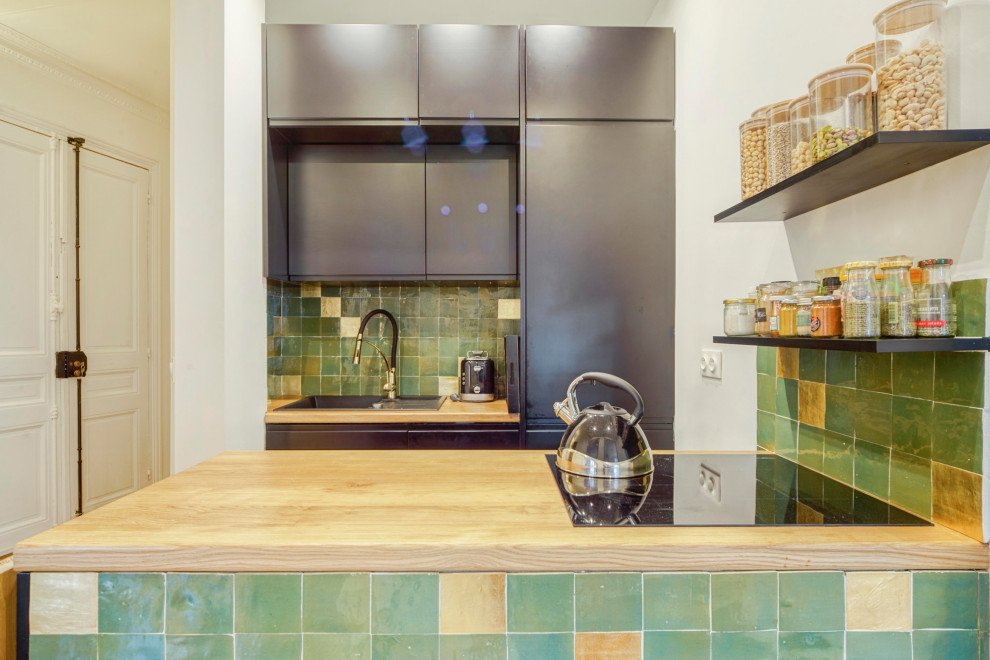 Immagine di una piccola cucina moderna con lavello sottopiano, ante lisce, ante nere, top in legno, paraspruzzi verde, paraspruzzi con piastrelle in terracotta, elettrodomestici da incasso, parquet chiaro, pavimento marrone e top beige