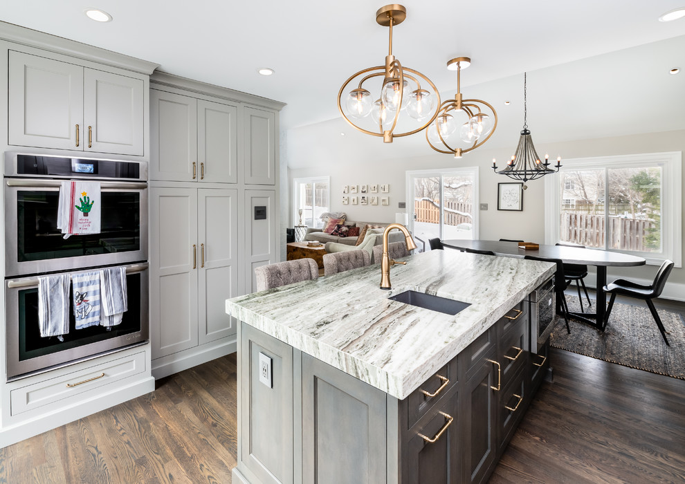 Mid-sized contemporary u-shaped eat-in kitchen in DC Metro with an undermount sink, shaker cabinets, white cabinets, white splashback, subway tile splashback, stainless steel appliances, dark hardwood floors, with island, brown floor and multi-coloured benchtop.