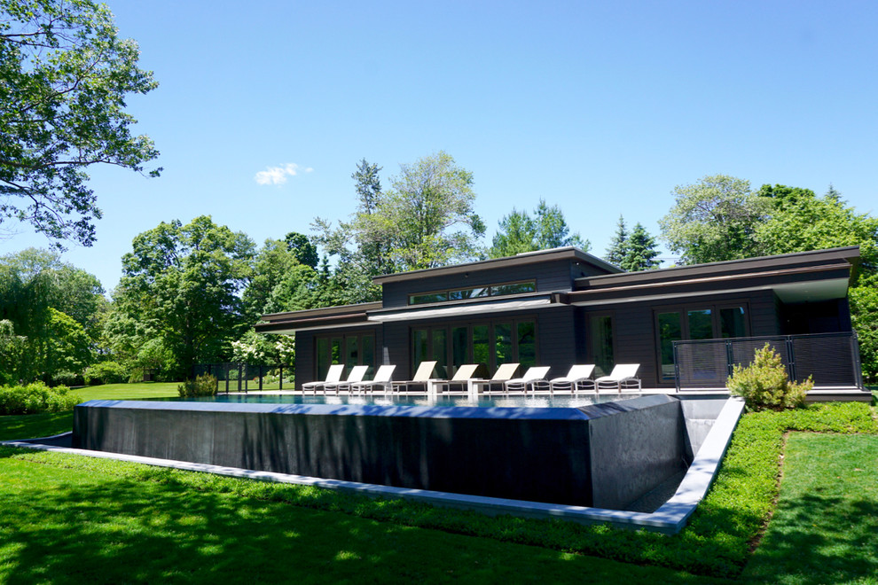 Large modern side yard rectangular infinity pool in Bridgeport with decking.