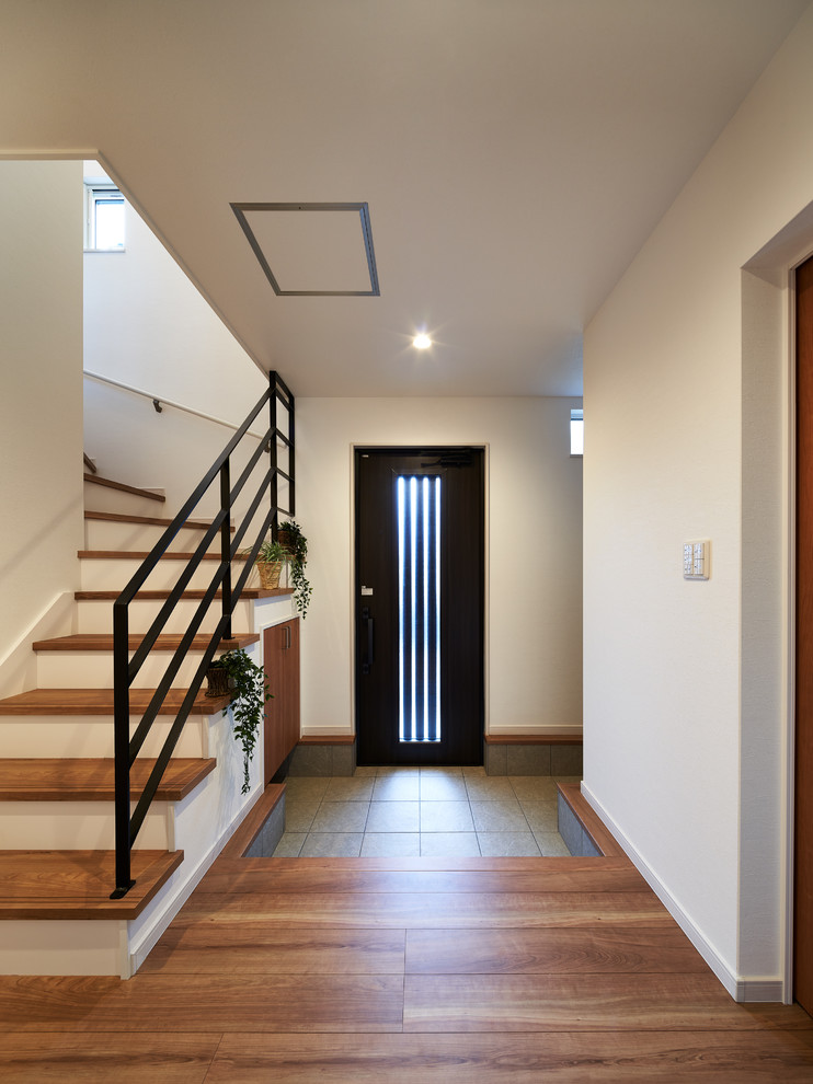 This is an example of a modern entry hall in Other with white walls, a single front door and a dark wood front door.