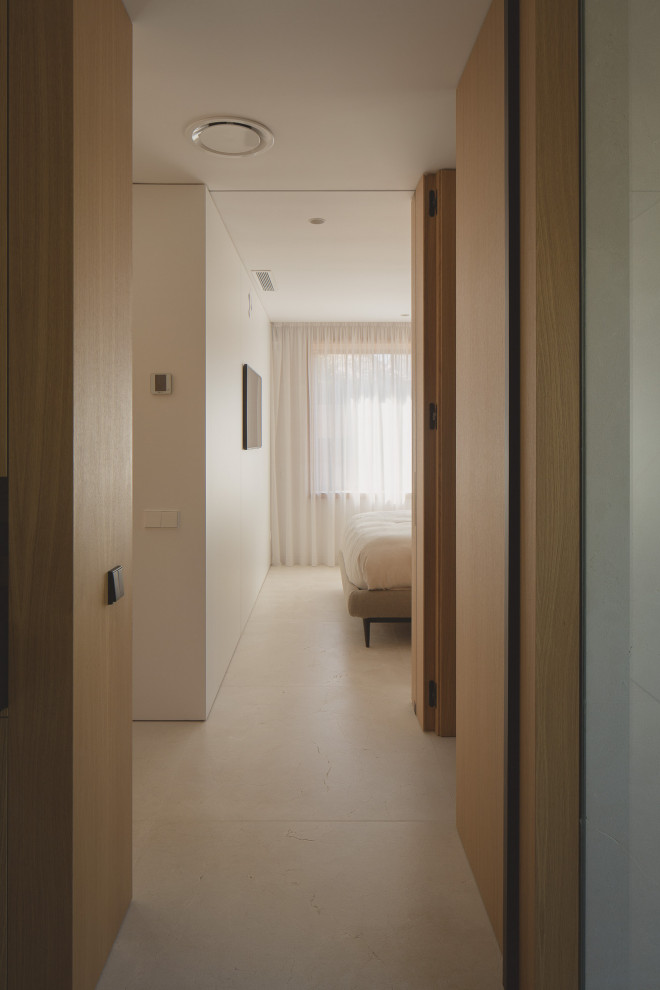 Réalisation d'une chambre parentale minimaliste en bois de taille moyenne avec un mur blanc et un sol en calcaire.