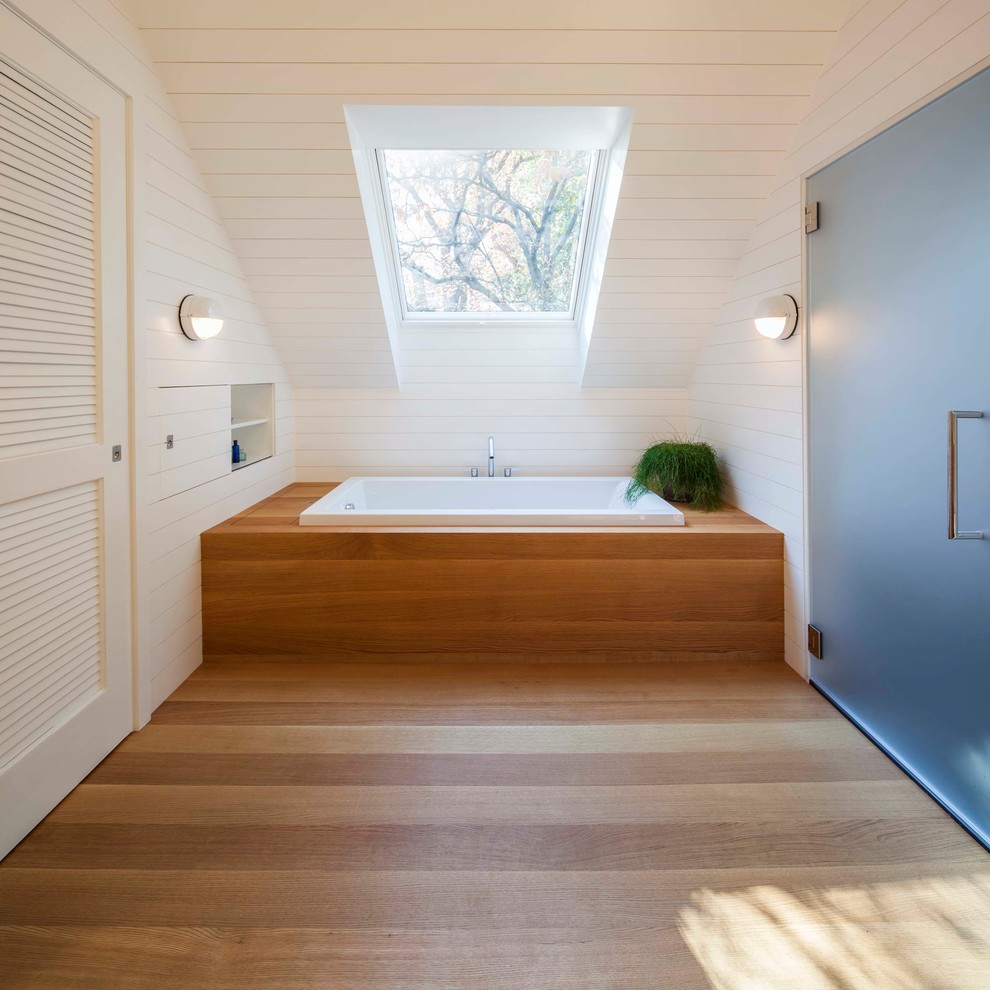 Beach style master bathroom in Boston with a drop-in tub, white walls and light hardwood floors.