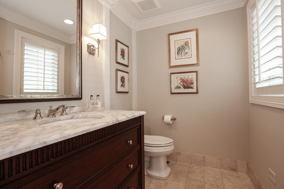 Mid-sized transitional powder room in Chicago with furniture-like cabinets, dark wood cabinets, a two-piece toilet, grey walls, ceramic floors, an undermount sink, engineered quartz benchtops and beige floor.