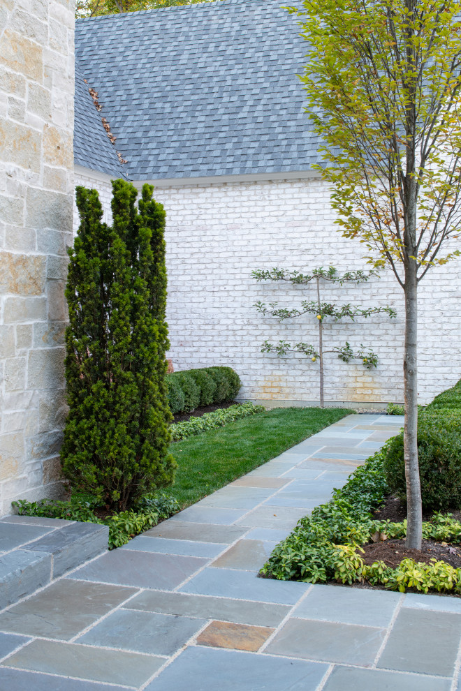 На фото: большой регулярный сад на внутреннем дворе в классическом стиле с дорожками и покрытием из каменной брусчатки