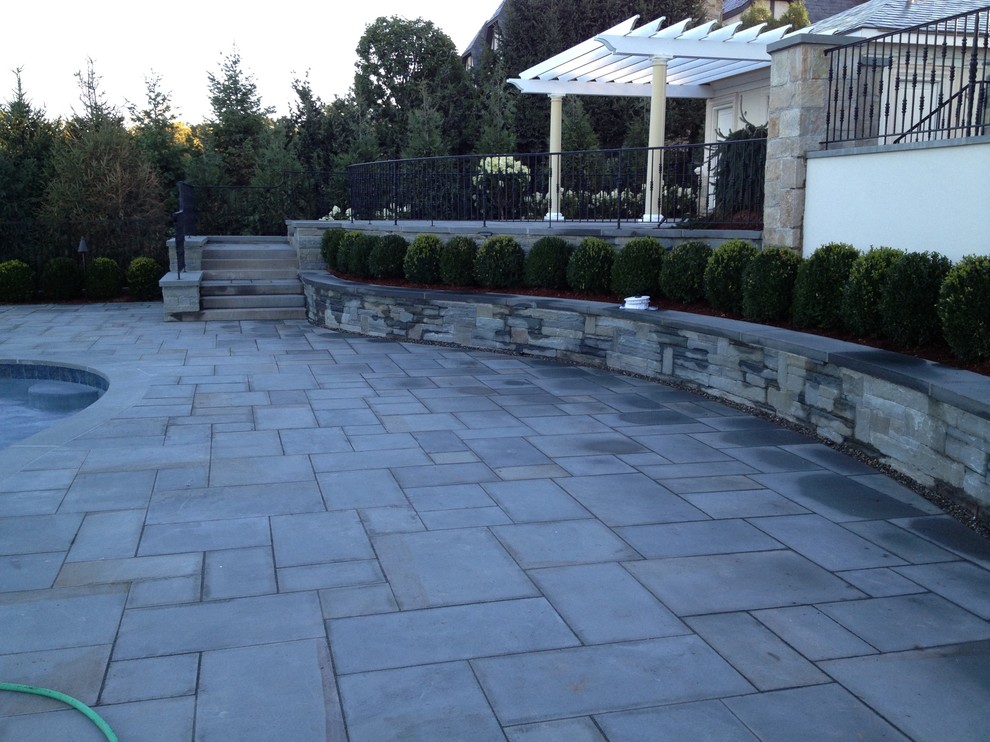 This is an example of a large contemporary backyard patio in New York with a water feature, natural stone pavers and a gazebo/cabana.