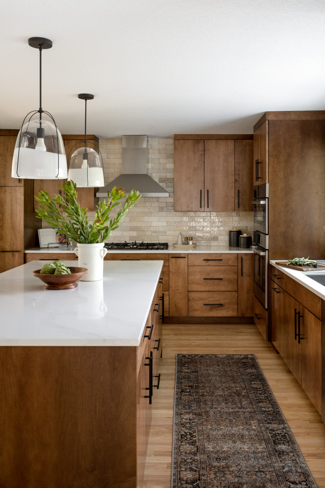 Mid-sized trendy galley medium tone wood floor enclosed kitchen photo in Seattle with an undermount sink, flat-panel cabinets, medium tone wood cabinets, quartz countertops, beige backsplash, subway tile backsplash, stainless steel appliances, an island and white countertops