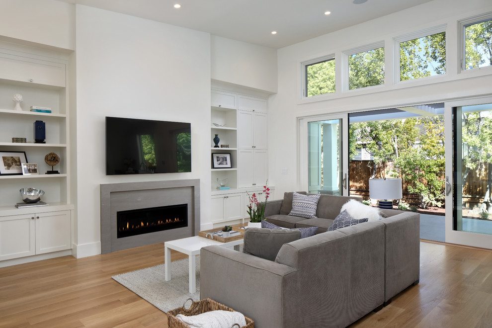 Inspiration for a large country formal open concept living room in San Francisco with white walls, medium hardwood floors, a standard fireplace, a concrete fireplace surround, a wall-mounted tv and brown floor.