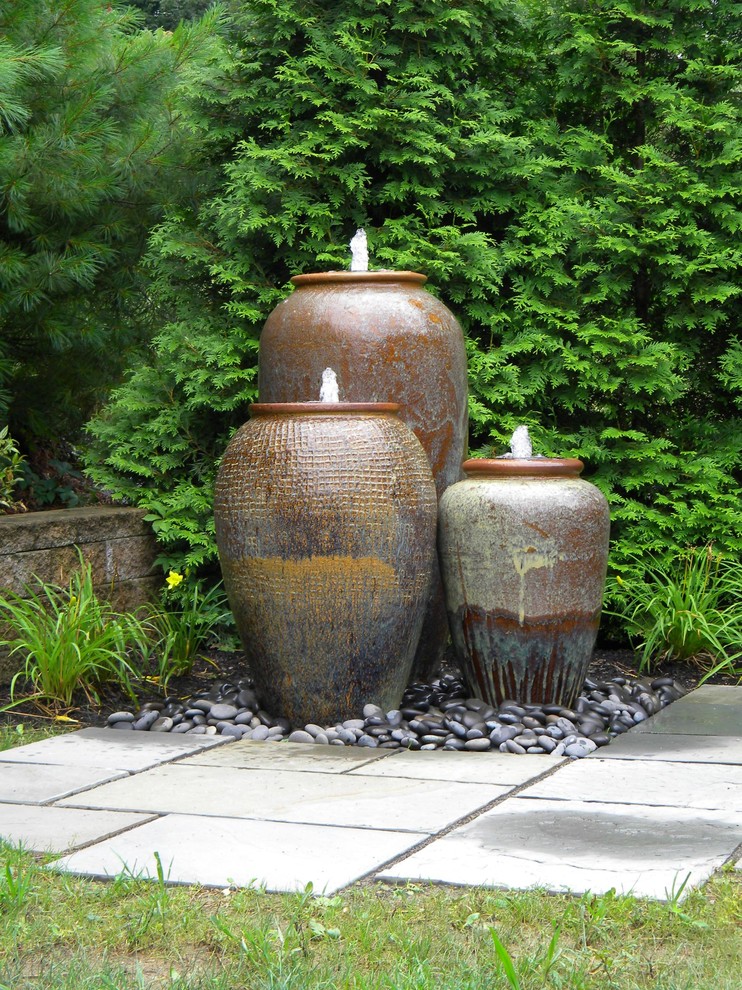 This is an example of a mid-sized traditional full sun backyard stone water fountain landscape for summer.