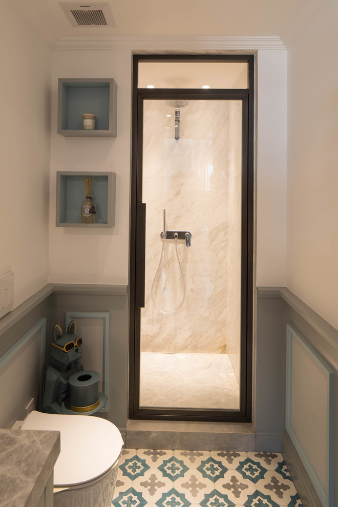 Photo of a mid-sized traditional 3/4 bathroom in Other with recessed-panel cabinets, grey cabinets, an alcove shower, a one-piece toilet, white tile, marble, multi-coloured walls, cement tiles, a drop-in sink, marble benchtops, multi-coloured floor, a hinged shower door and grey benchtops.