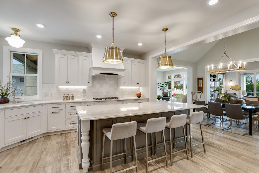 Inspiration for a large u-shaped eat-in kitchen in Minneapolis with an undermount sink, beaded inset cabinets, white cabinets, quartzite benchtops, white splashback, ceramic splashback, stainless steel appliances, light hardwood floors, with island and beige benchtop.