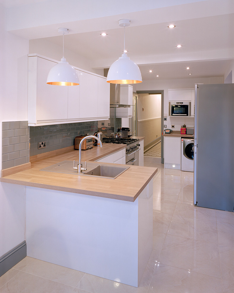 Design ideas for a small modern l-shaped eat-in kitchen in West Midlands with a drop-in sink, flat-panel cabinets, white cabinets, wood benchtops, grey splashback, ceramic splashback, travertine floors and a peninsula.