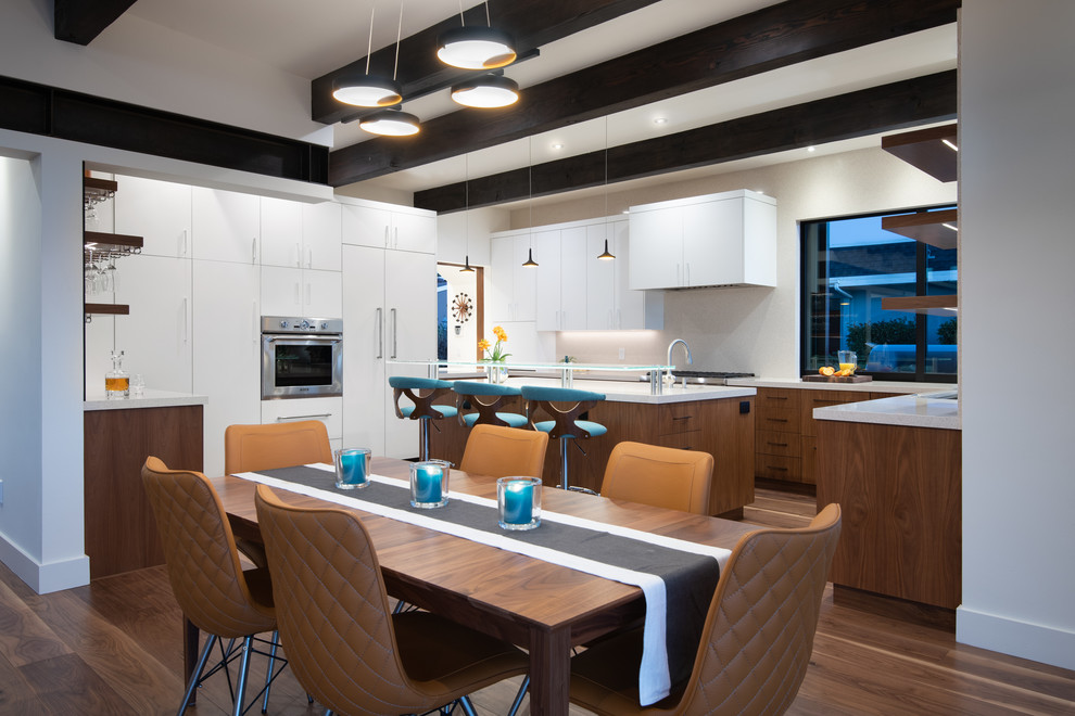 This is an example of a mid-sized u-shaped eat-in kitchen in San Diego with an undermount sink, flat-panel cabinets, white cabinets, quartz benchtops, beige splashback, panelled appliances, medium hardwood floors, with island and beige benchtop.