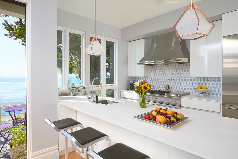 Photo of a contemporary galley open plan kitchen in New York with an undermount sink, flat-panel cabinets, white cabinets, multi-coloured splashback, stainless steel appliances, a peninsula and quartz benchtops.