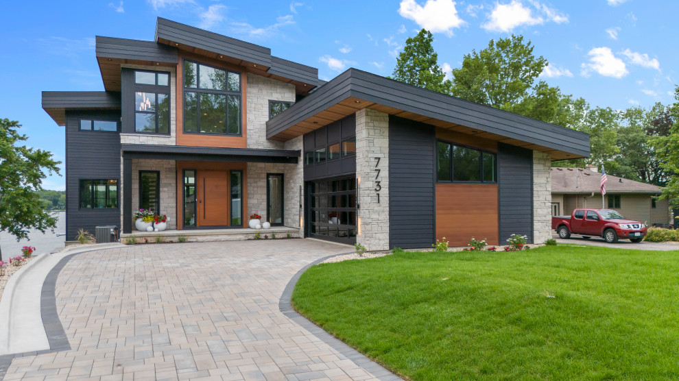 Large trendy multicolored two-story mixed siding house exterior photo in Other with a shed roof and a black roof