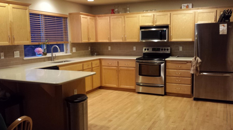 Example of a medium tone wood floor kitchen design in Seattle with flat-panel cabinets, medium tone wood cabinets, granite countertops, beige backsplash and an island
