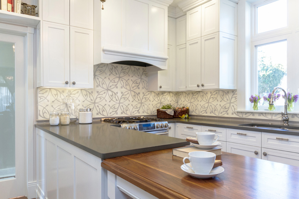 Example of a mid-sized transitional galley medium tone wood floor enclosed kitchen design with a single-bowl sink, recessed-panel cabinets, white cabinets, quartz countertops, beige backsplash, ceramic backsplash, stainless steel appliances and a peninsula