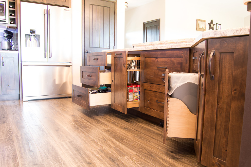 Inspiration for a rustic l-shaped brown floor eat-in kitchen remodel with shaker cabinets, brown cabinets, laminate countertops, gray backsplash, stainless steel appliances, an island and beige countertops