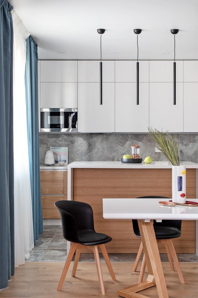 Photo of a mid-sized contemporary single-wall open plan kitchen in Other with an integrated sink, flat-panel cabinets, medium wood cabinets, solid surface benchtops, grey splashback, porcelain splashback, stainless steel appliances, porcelain floors, with island, grey floor and white benchtop.