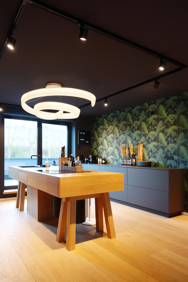 Inspiration for a large contemporary galley kitchen in Hanover with a drop-in sink, flat-panel cabinets, black cabinets, multi-coloured splashback, with island, brown floor, black benchtop and wallpaper.