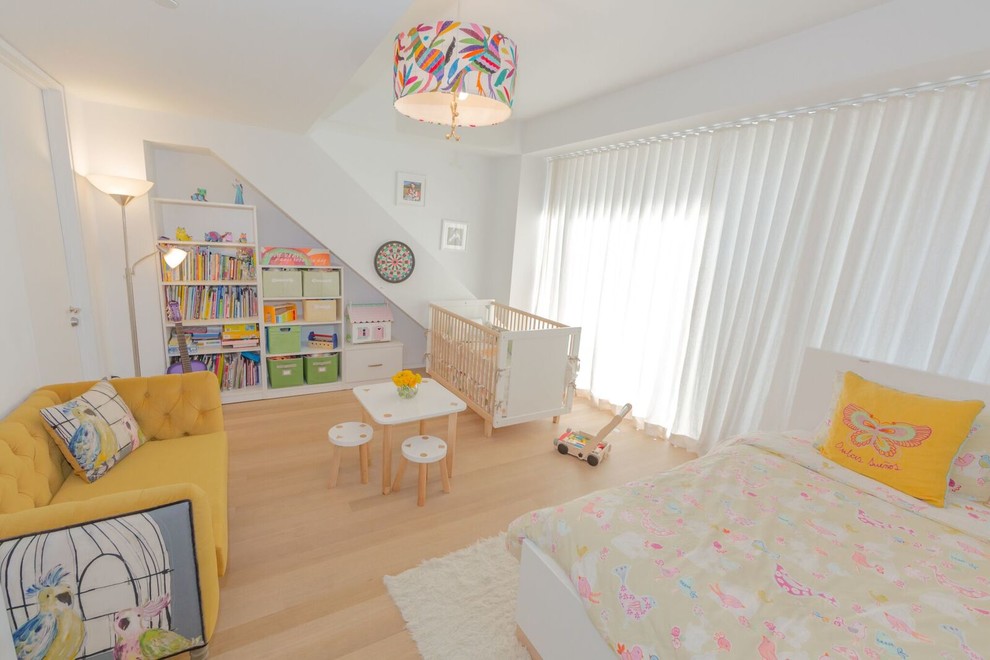 Design ideas for a mid-sized transitional nursery for girls in Los Angeles with white walls and light hardwood floors.