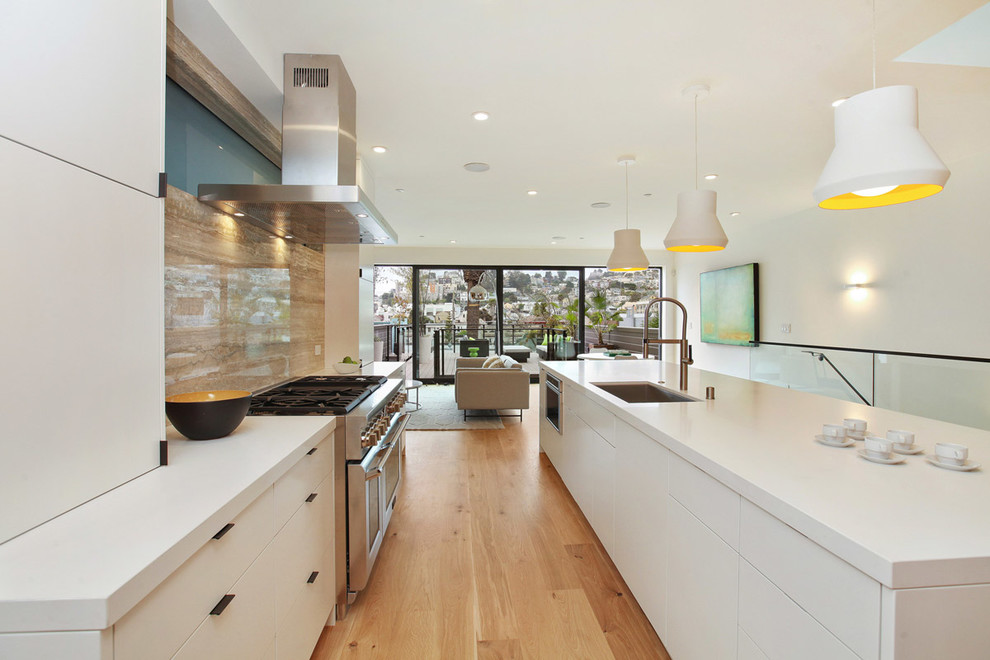 Photo of a contemporary galley kitchen in San Francisco with an undermount sink, flat-panel cabinets, white cabinets, beige splashback, stainless steel appliances, medium hardwood floors and with island.
