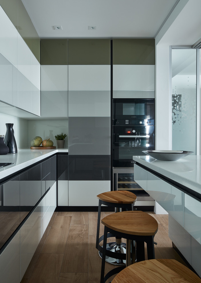 Small scandinavian separate kitchen in Moscow with flat-panel cabinets, white splashback, medium hardwood floors, grey cabinets, black appliances and a peninsula.