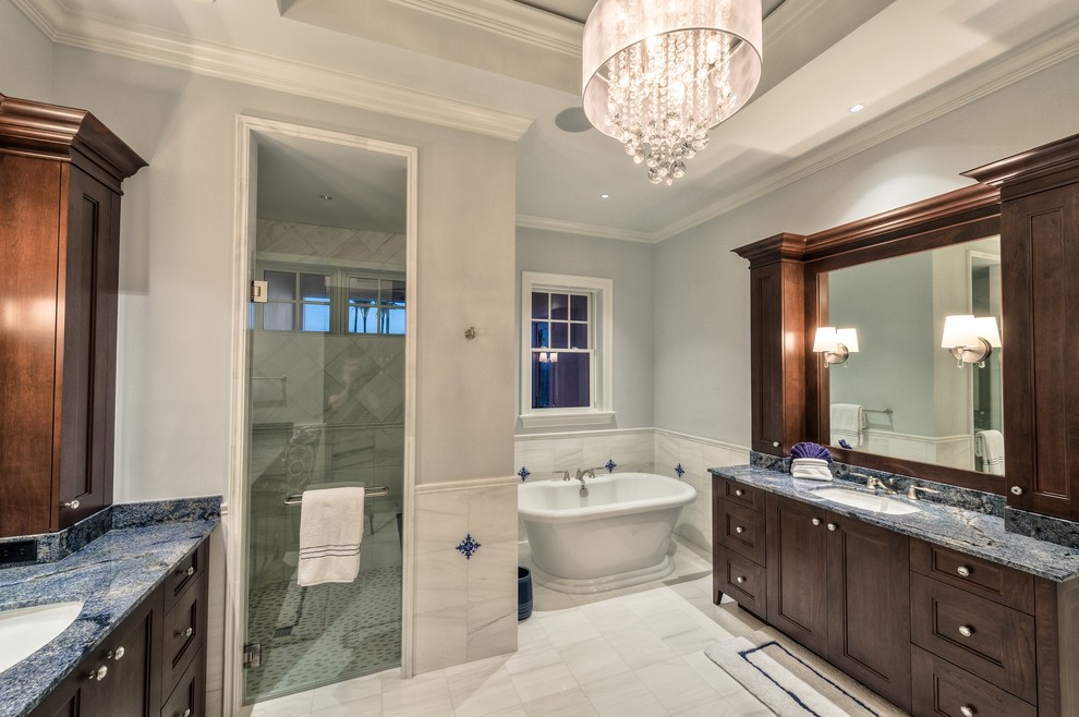 Photo of a beach style master bathroom in Miami with shaker cabinets, dark wood cabinets, a freestanding tub, a double shower, a one-piece toilet, white tile, stone tile, marble floors, an undermount sink and marble benchtops.