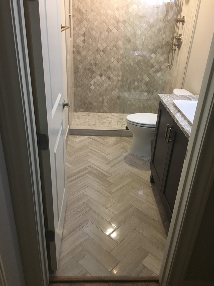 Inspiration for a mid-sized modern 3/4 bathroom in Austin with recessed-panel cabinets, grey cabinets, an alcove shower, a two-piece toilet, gray tile, limestone, grey walls, limestone floors, a drop-in sink and engineered quartz benchtops.