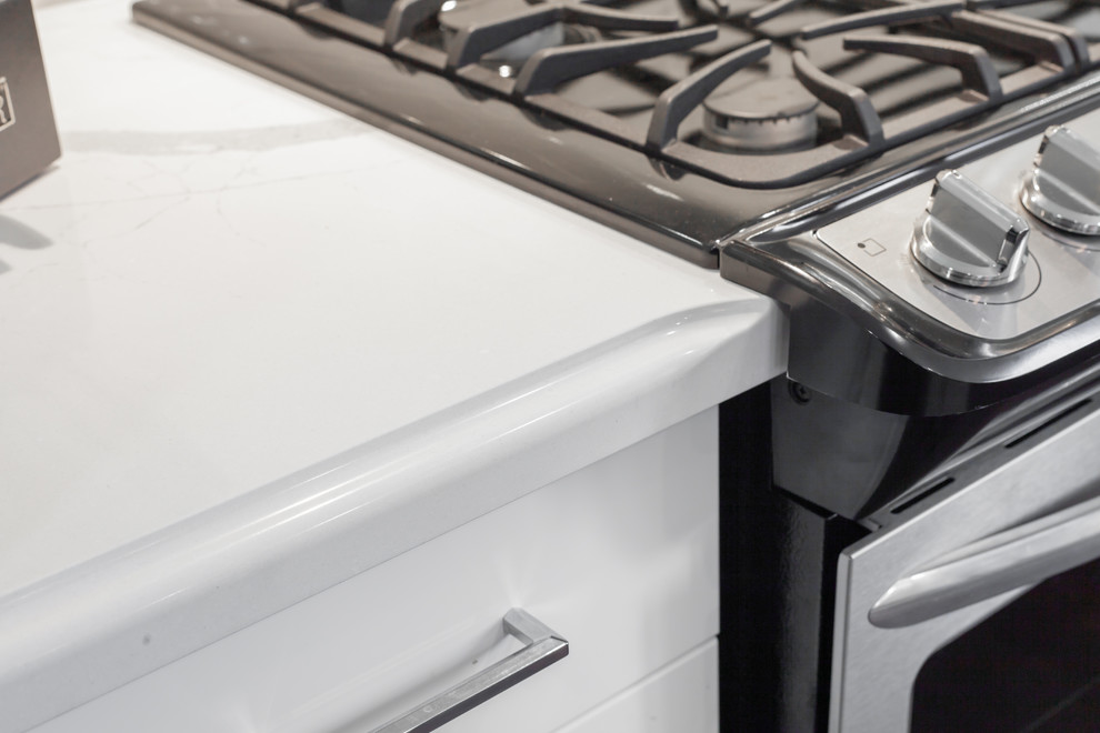 Example of a large transitional l-shaped medium tone wood floor and brown floor enclosed kitchen design with an undermount sink, recessed-panel cabinets, white cabinets, quartz countertops, gray backsplash, ceramic backsplash, stainless steel appliances, an island and white countertops