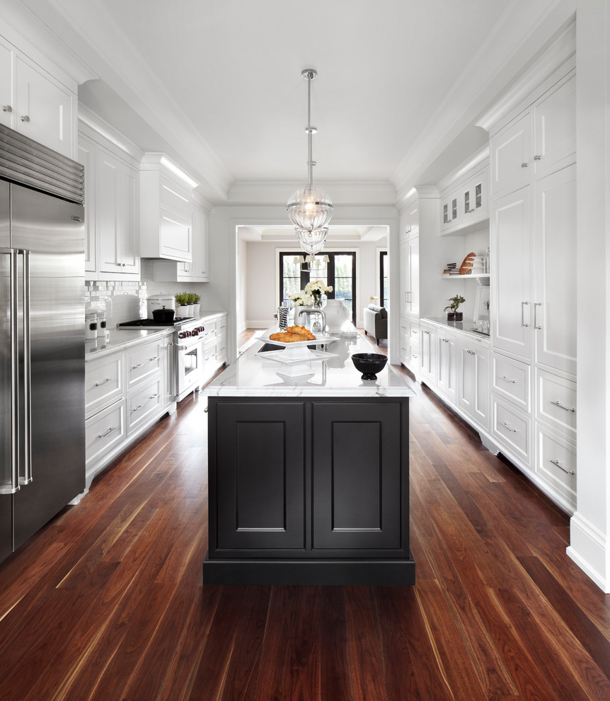 Transitional galley kitchen in Toronto with recessed-panel cabinets, white cabinets, white splashback, subway tile splashback, stainless steel appliances, dark hardwood floors, with island and brown floor.