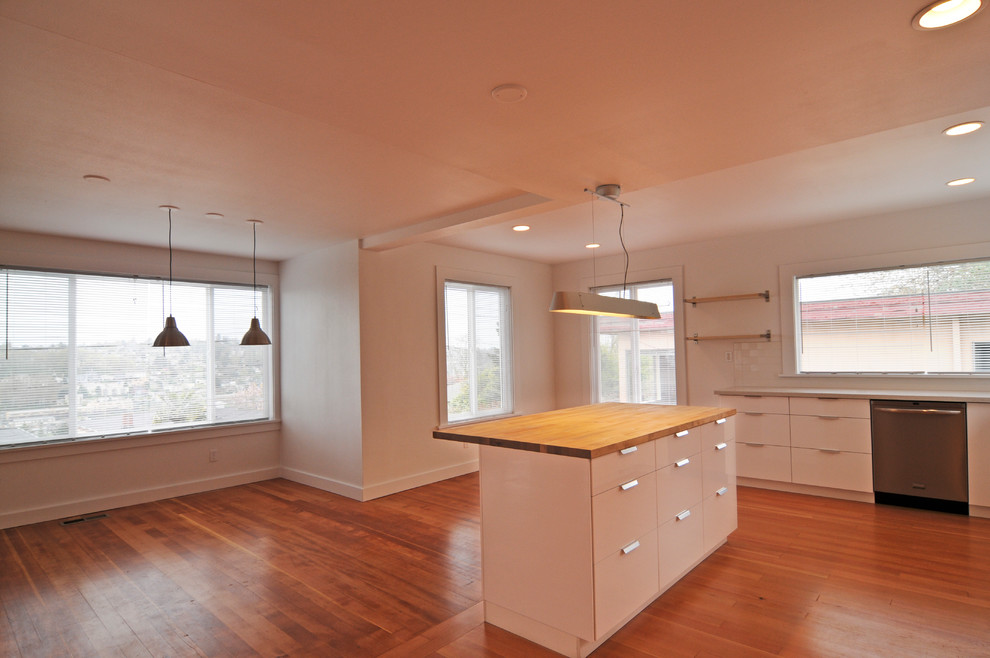 Inspiration for a timeless l-shaped medium tone wood floor eat-in kitchen remodel in Seattle with an undermount sink, white cabinets, white backsplash, stainless steel appliances and an island