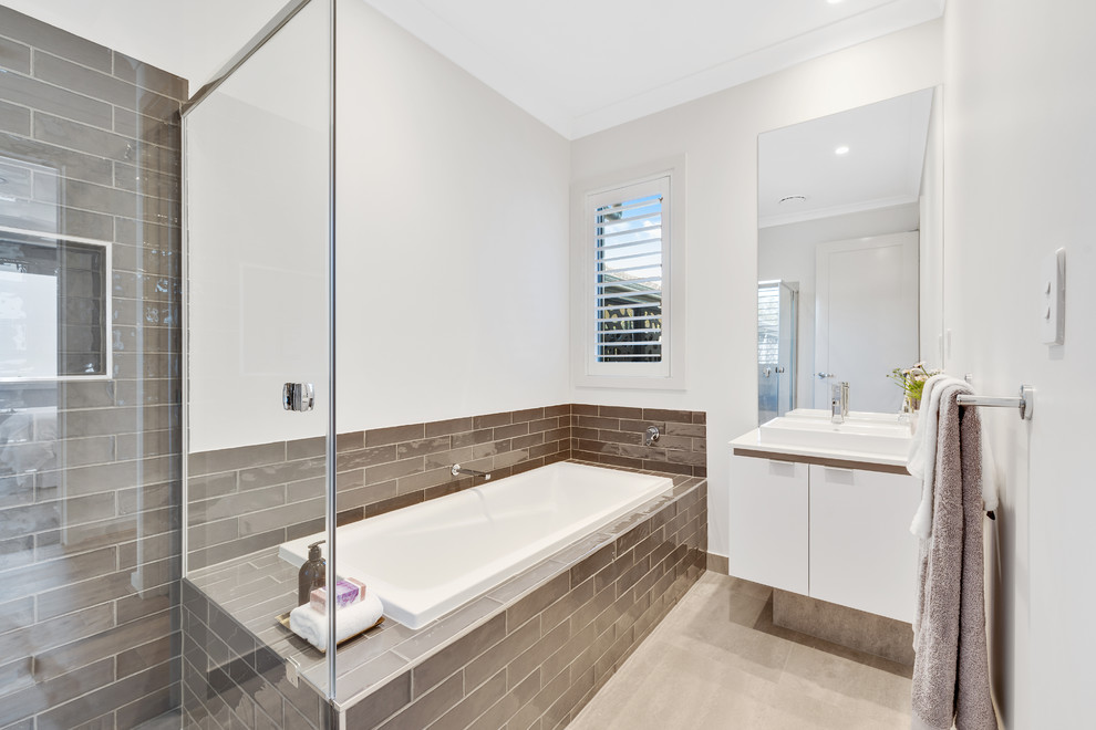 Photo of a beach style master bathroom in Brisbane with flat-panel cabinets, white cabinets, a drop-in tub, a corner shower, brown tile, subway tile, white walls, a drop-in sink, beige floor, a hinged shower door and white benchtops.