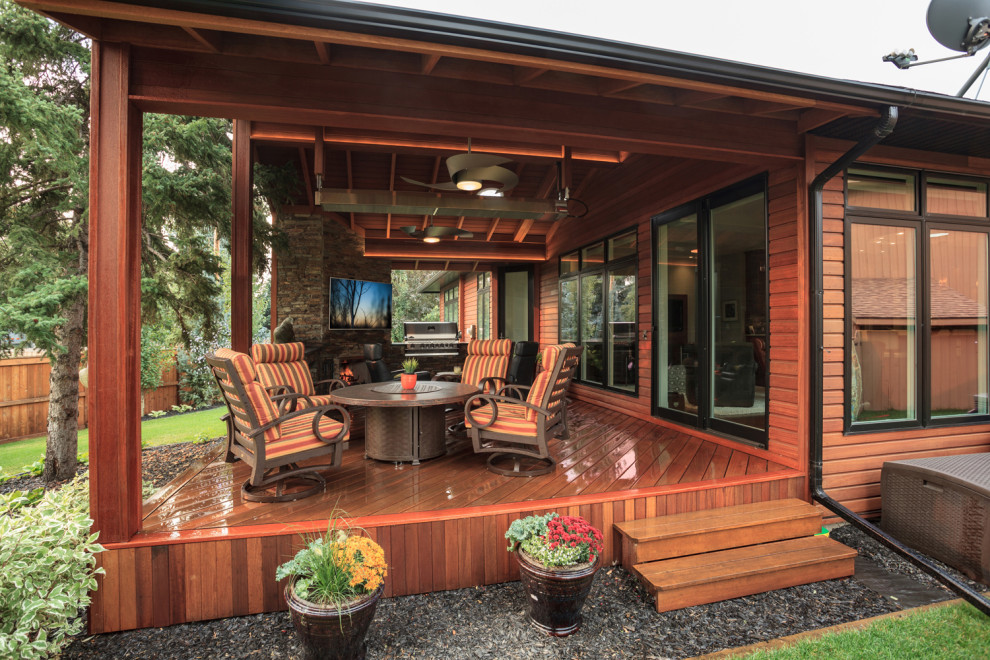Example of a mid-sized transitional backyard deck design in Calgary with a roof extension