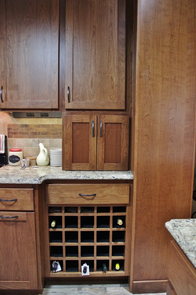 Enclosed kitchen - mid-sized transitional galley ceramic tile enclosed kitchen idea with an undermount sink, shaker cabinets, medium tone wood cabinets, quartz countertops, beige backsplash, stone tile backsplash, stainless steel appliances and a peninsula