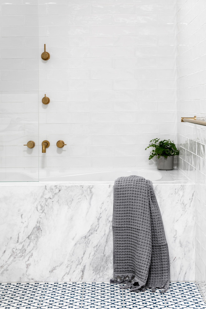This is an example of a mid-sized transitional master bathroom in Melbourne with recessed-panel cabinets, white cabinets, an undermount tub, a shower/bathtub combo, white tile, subway tile, marble benchtops, a hinged shower door, a two-piece toilet, blue walls, porcelain floors, a vessel sink and blue floor.