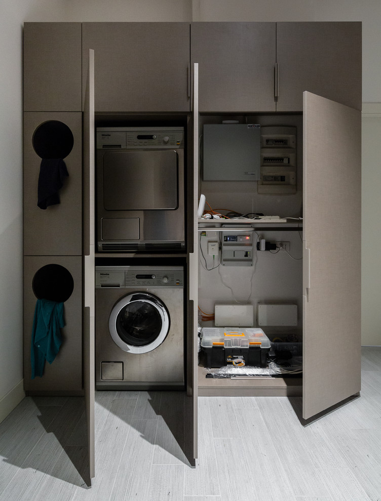 This is an example of a mid-sized eclectic single-wall utility room in Milan with a drop-in sink, open cabinets, grey cabinets, laminate benchtops, grey walls, dark hardwood floors, a concealed washer and dryer and grey floor.