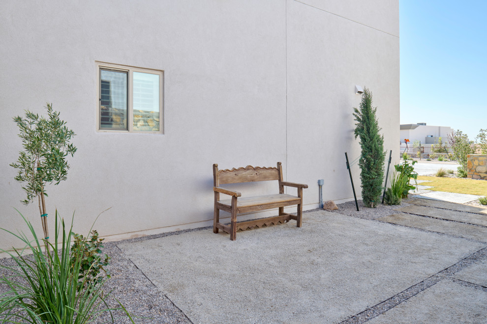 Aménagement d'un jardin arrière contemporain de taille moyenne avec une exposition ensoleillée, du gravier et une clôture en pierre.